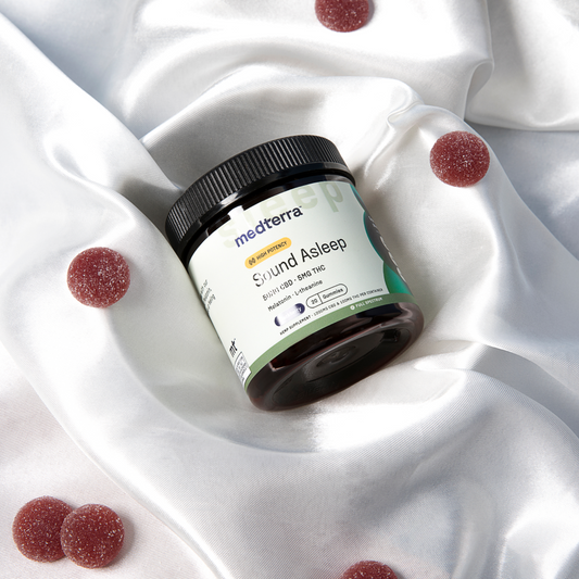 Jar of Medterra Sound Asleep gummies with label showing 50MG CBD, 5MG THC, Melatonin, L-theanine, Blackberry flavor, 20 gummies, and full spectrum hemp. Three sugar-coated red gummies are placed beside the jar.