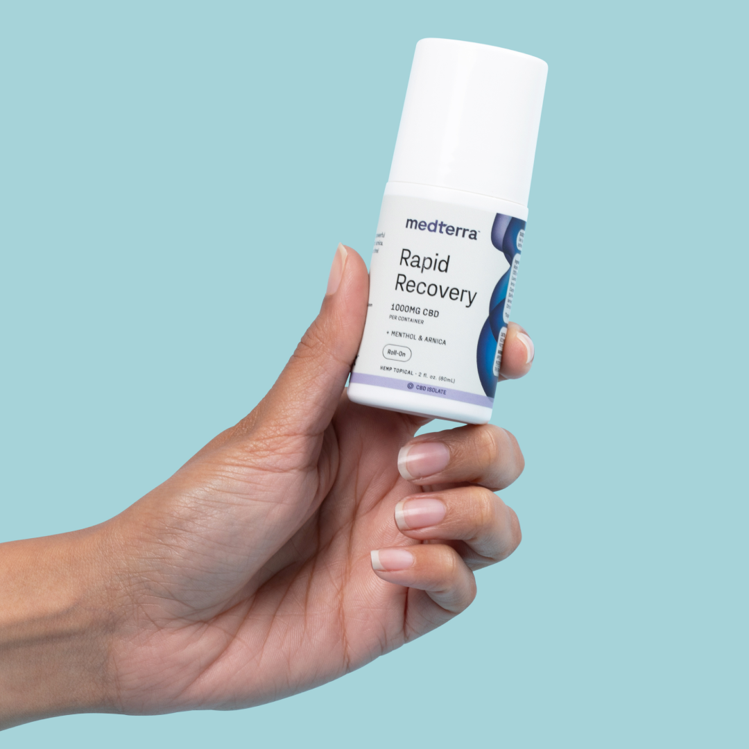 A hand holds a white bottle labeled "Medterra Rapid Recovery CBD Roll On 1000mg CBD + Arnica." The blue and white packaging indicates it is a CBD roll-on product for pain relief with a rapid cooling effect. The background is a solid light blue color.