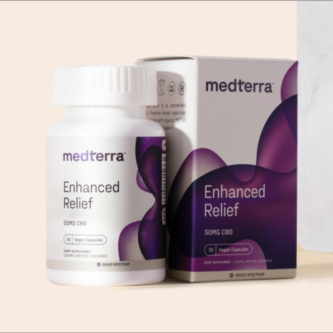 A bottle and box of Medterra Enhanced Relief Broad Spectrum Capsules, showcasing "50MG CBD" and "Vegan Capsules." The white container with a purple abstract design prominently features the brand name "Medterra." This product utilizes Broad Spectrum CBD. The background is a neutral beige.