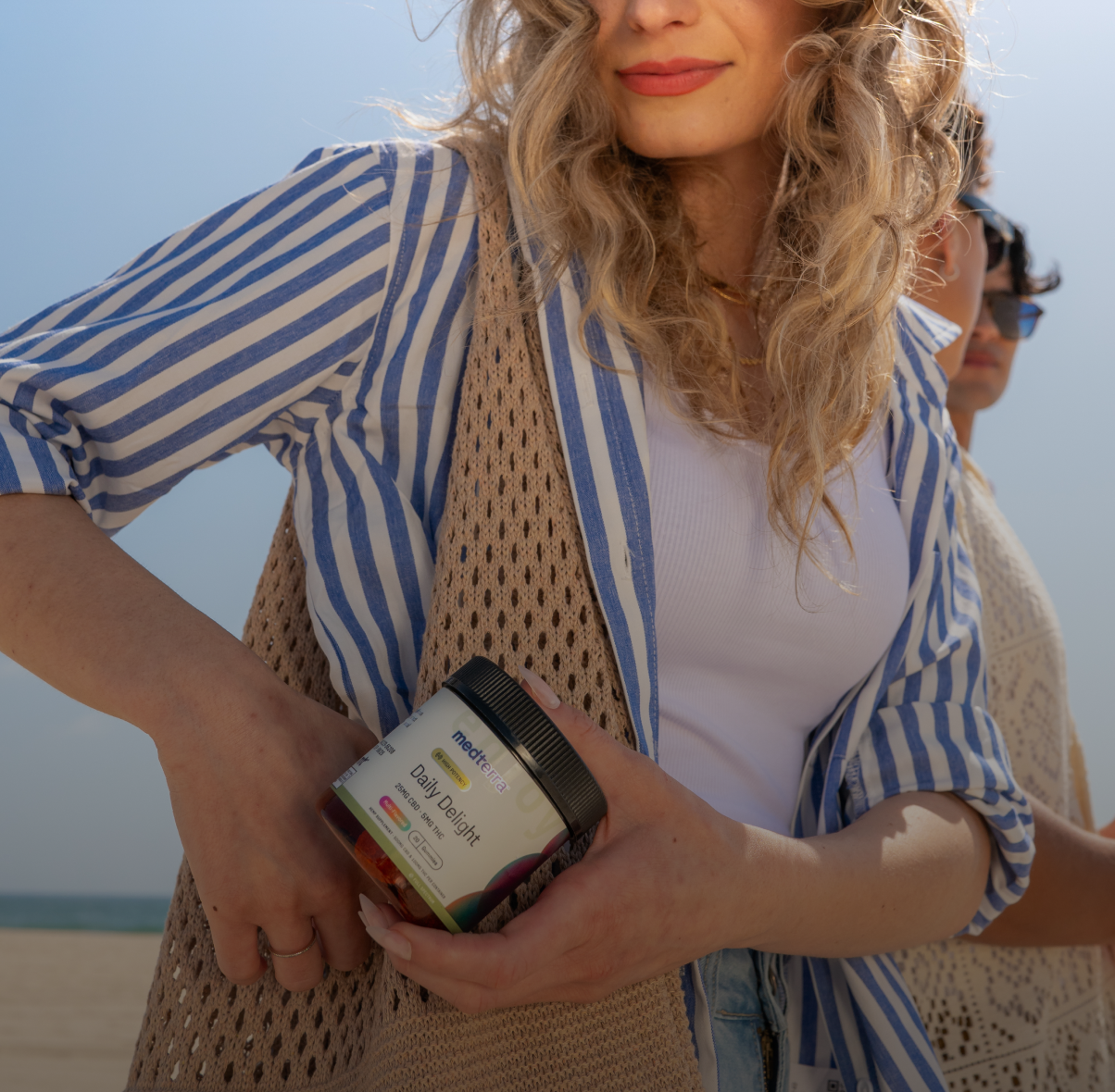 A woman holding a jar of MaryRuth Organics Daily Greens outdoors on a sunny day.