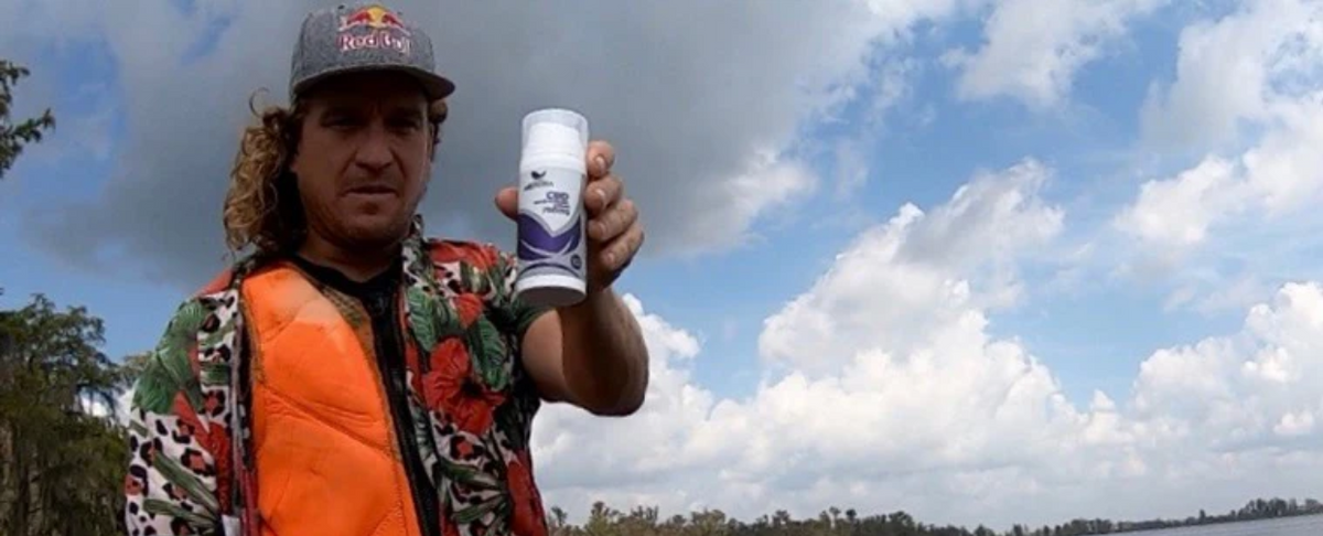 Man wearing a Red Bull cap and orange life vest holding a Medterra CBD Relief Cream container