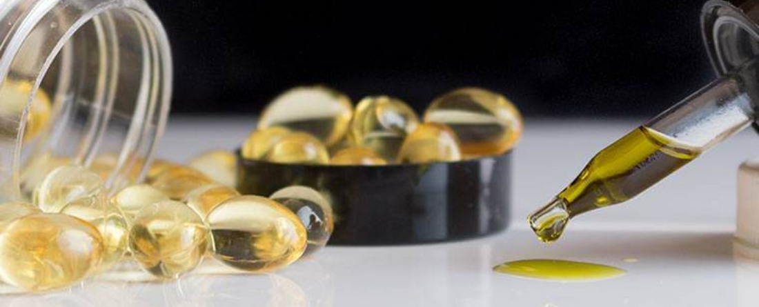 CBD capsules and oil dropper on a white surface
