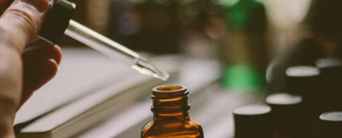 A dropper dispensing CBD oil from a brown glass bottle