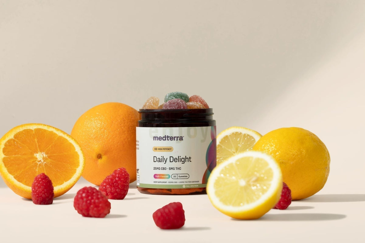 Front view of Medterra Daily Delight jar with open gummies labeled 25mg CBD 5mg THC and orange, lemon, raspberries