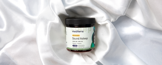  A jar of Medterra Sound Asleep CBD gummies is placed on a white silky fabric background.