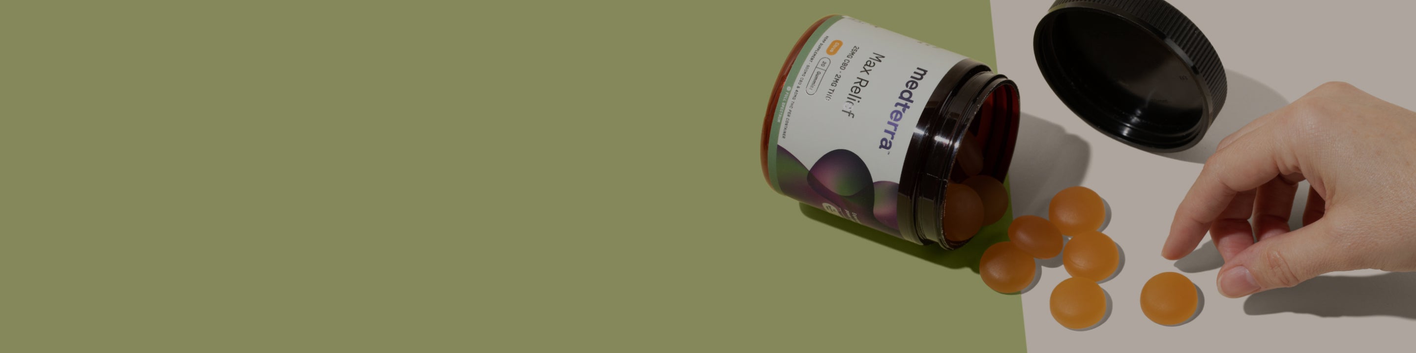 A hand reaches for a soft chew from an open container labeled "medterra Fast Relief." The transparent container is partially filled with circular, amber-colored chews, some of which are scattered on a green surface. The background is a muted green.