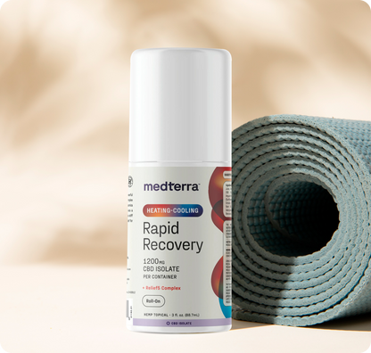 A Medterra Heating-Cooling Rapid Recovery Roll On stands upright beside a rolled-up blue yoga mat on a beige surface, with a soft, neutral background—showcasing convenient pain relief for your active lifestyle.