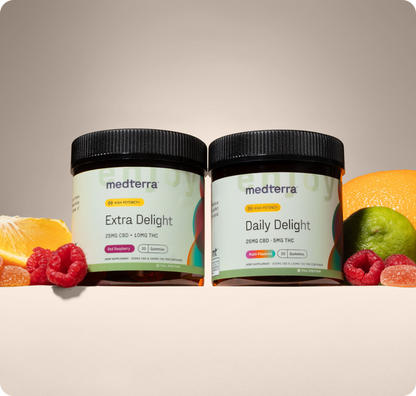 Two Medterra gummy containers—Extra Delight 10mg THC Gummies and Daily Delight—are shown with raspberries, orange slices, a lime, and high-potency CBD gummies against a neutral background.