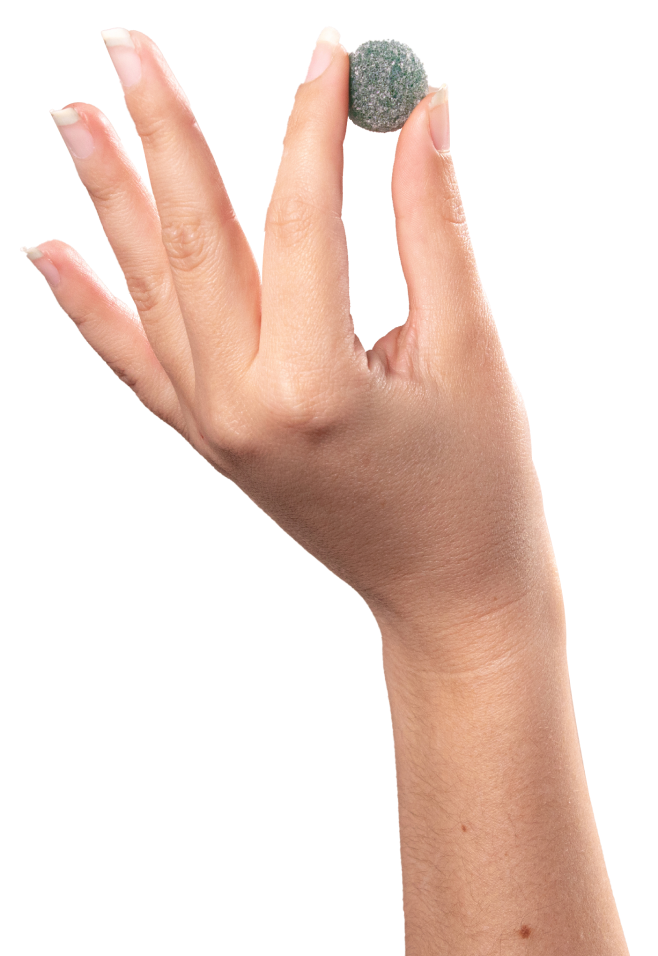 A close-up image showcases a hand with neatly manicured nails holding a small, round, greenish-gray object between its thumb and index finger. The background is plain white, highlighting the quality pure ingredients sourced from the USA, reminiscent of Medterra's commitment to excellence.