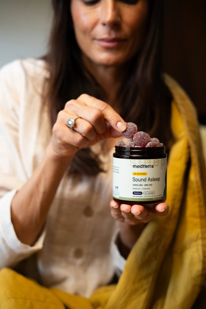 Woman taking a gummy from a jar of Medterra Sound Asleep